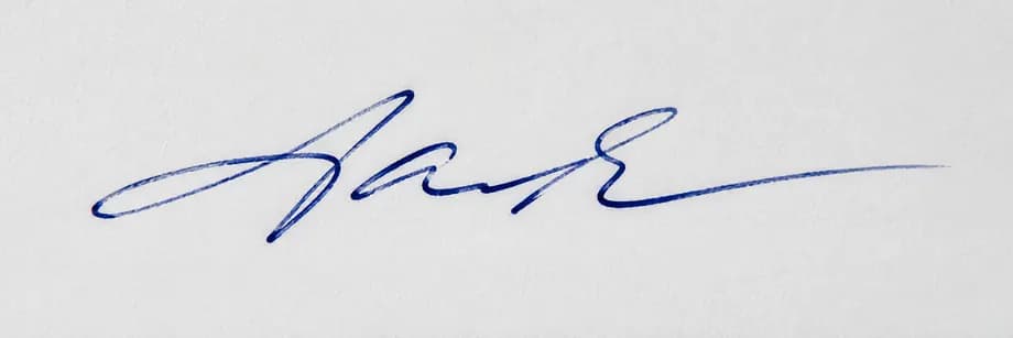 Handwritten signature in blue ink on white paper before conversion to a transparent PNG
